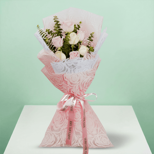 Hand -tied bouquet of pink and peach roses with eucalyptus in a pink wrap