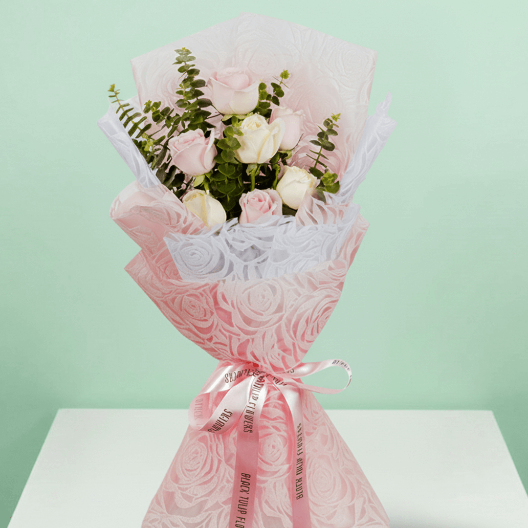 Hand -tied bouquet of pink and peach roses with eucalyptus in a pink wrap