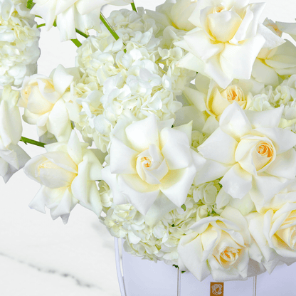 White hydrangea and rose arrangement with 30 blooms in a round white flower box.