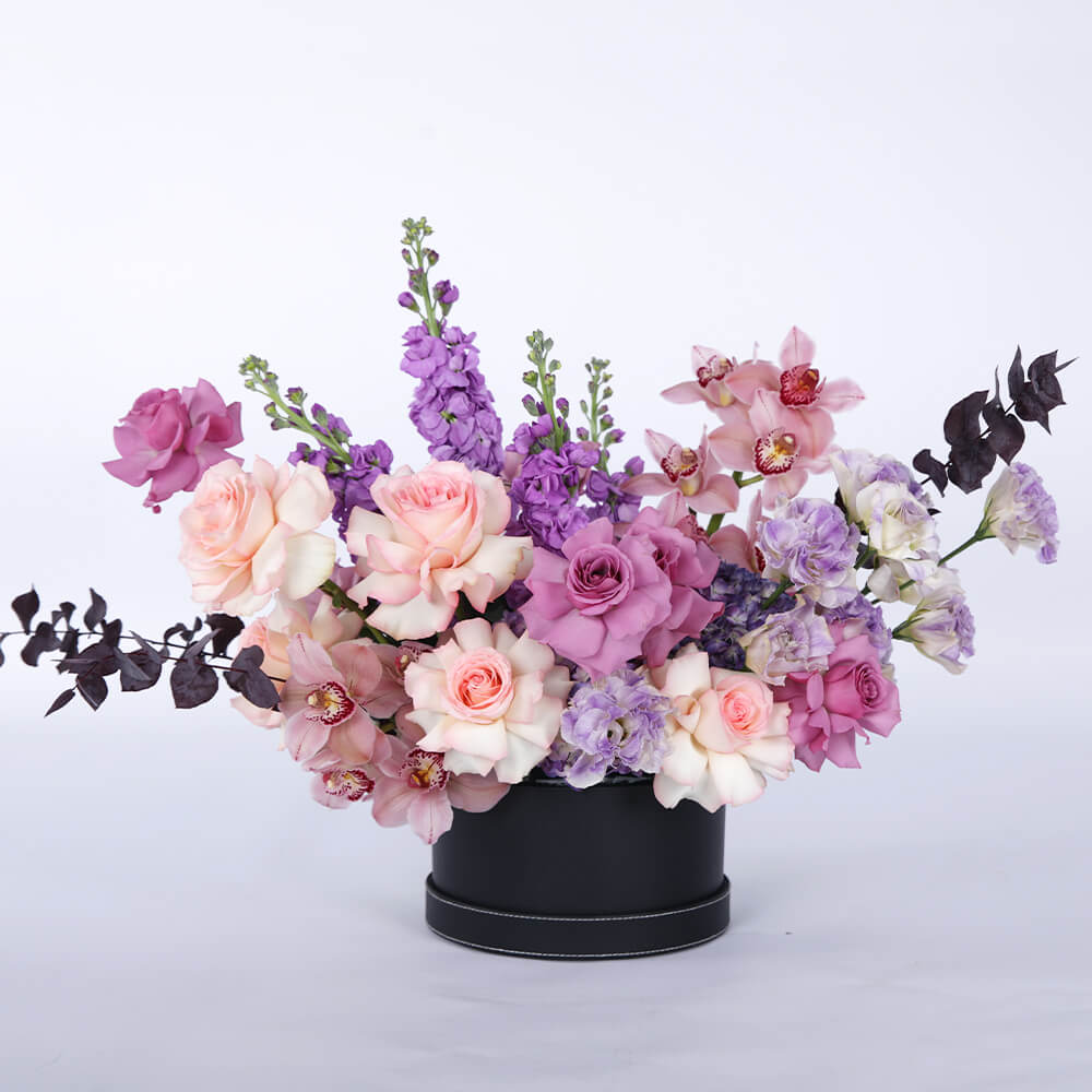 Pastel Roses, Cymbidium orchids, Lisianthus, Hydrangeas and Snapdragons arranged in a black round flower box.