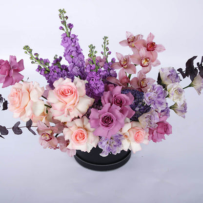 Pastel Roses, Cymbidium orchids, Lisianthus, Hydrangeas and Snapdragons arranged in a black round flower box.