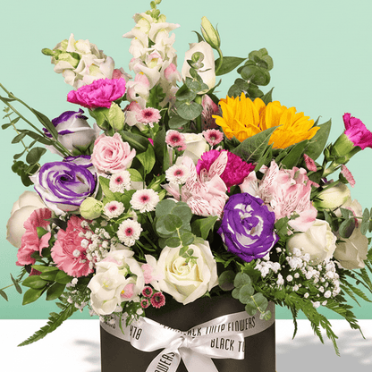 A round flower box arranged with sunflowers, roses, Eustoma, snapdragons, alstroemeria and carnations.