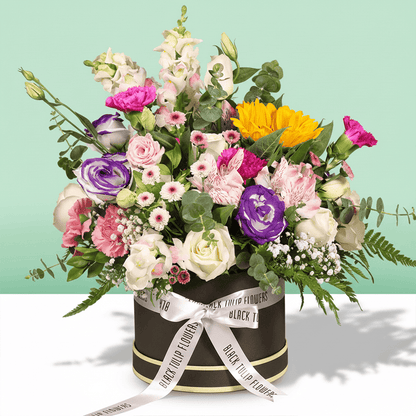 A round flower box arranged with sunflowers, roses, Eustoma, snapdragons, alstroemeria and carnations.