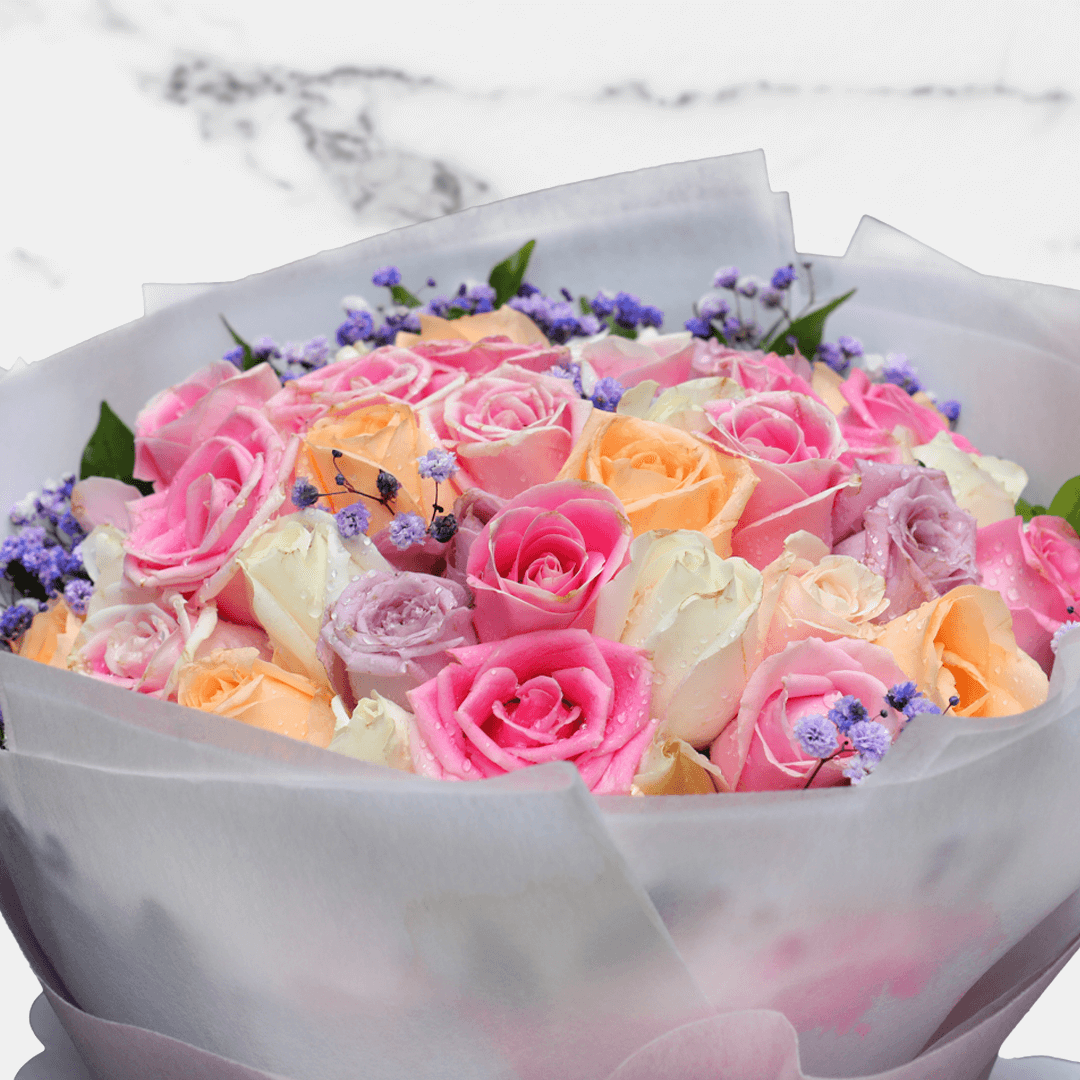 Premium bouquet of assorted pink, peach, lavender and white roses with purple gypsophila wrapped in non-woven paper