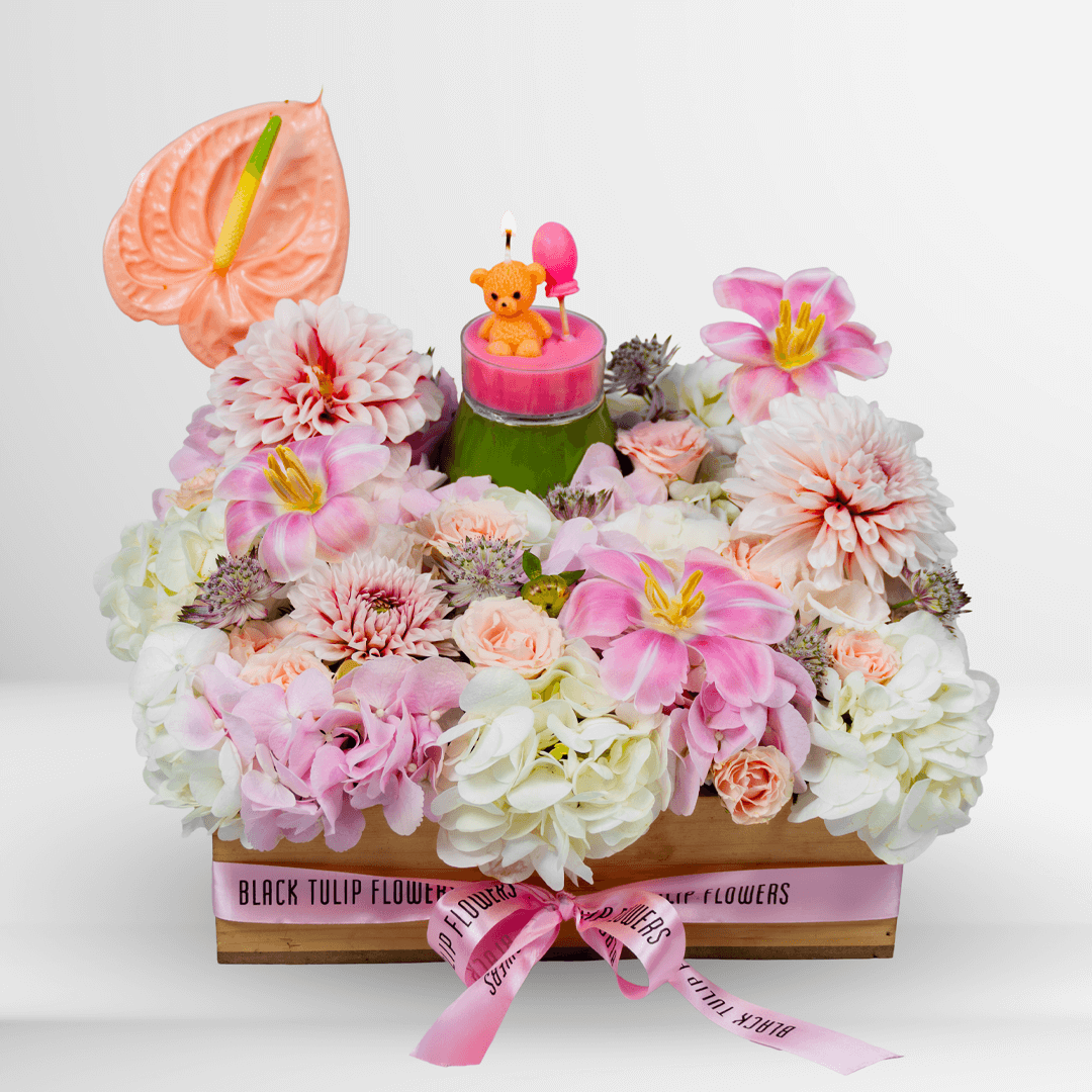 Pink lily, hydrangea and dahlia flower arrangement with anthurium, teddy bear candle and balloon in a wooden crate