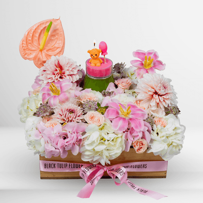 Pink lily, hydrangea and dahlia flower arrangement with anthurium, teddy bear candle and balloon in a wooden crate