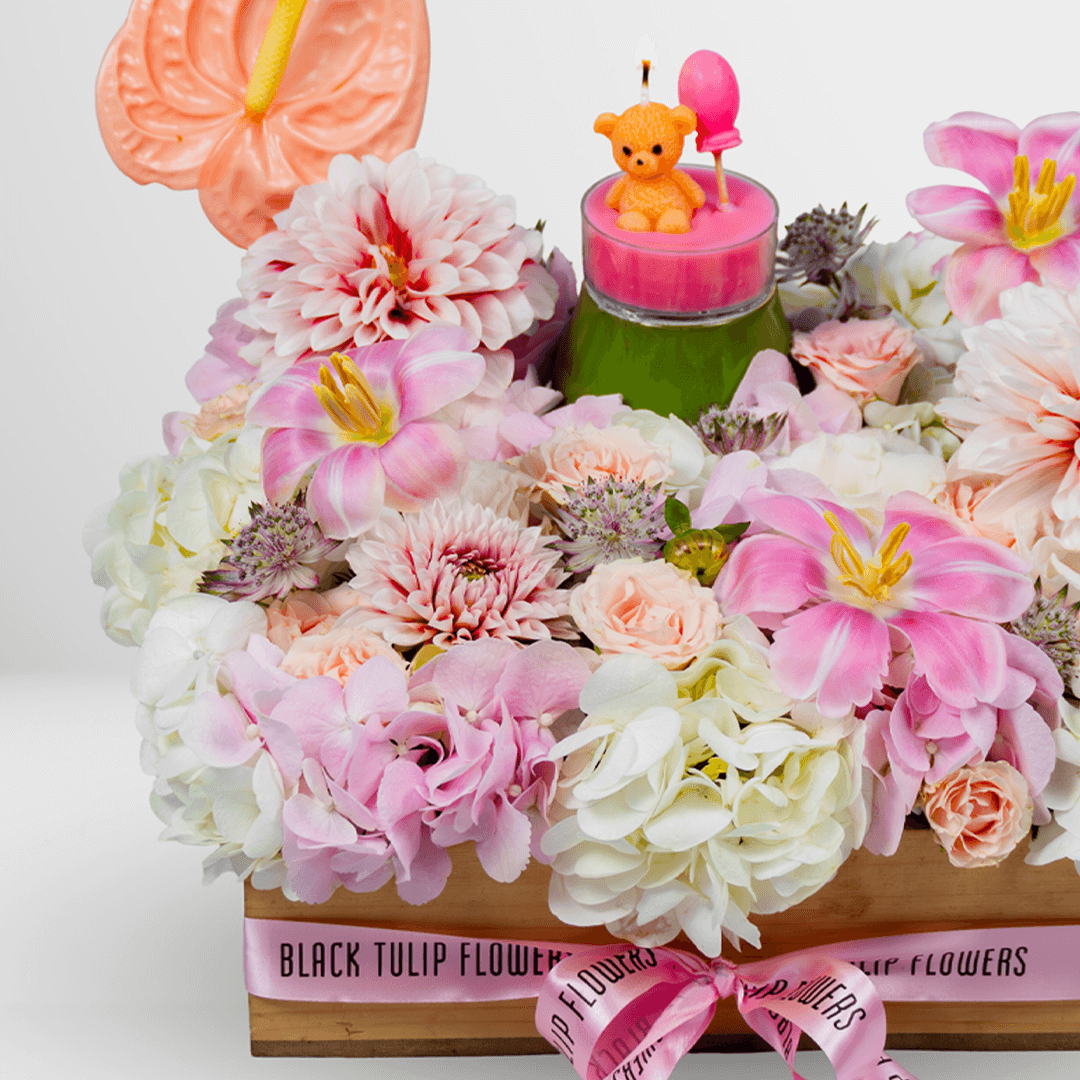 Pink lily, hydrangea and dahlia flower arrangement with anthurium, teddy bear candle and balloon in a wooden crate