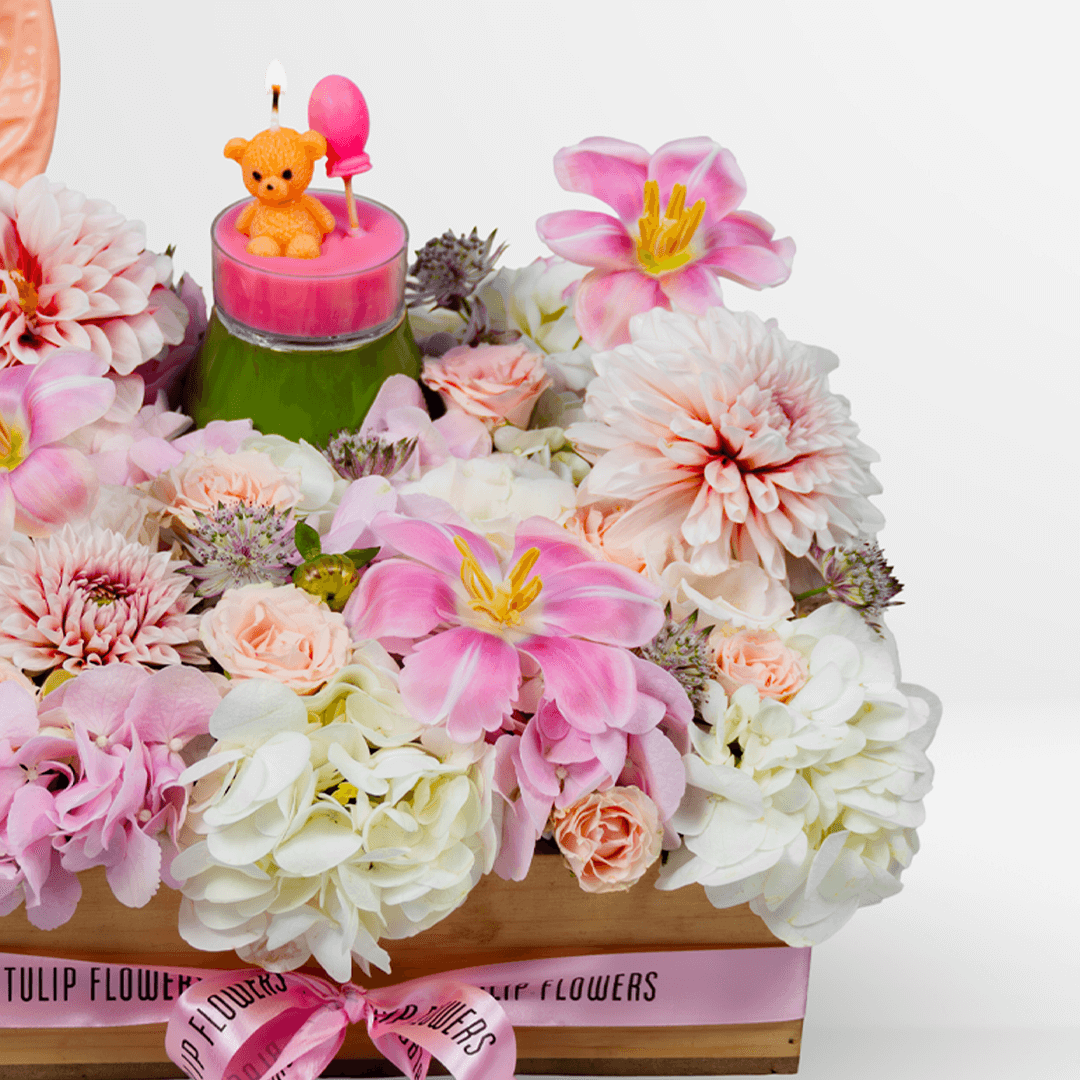 Pink lily, hydrangea and dahlia flower arrangement with anthurium, teddy bear candle and balloon in a wooden crate