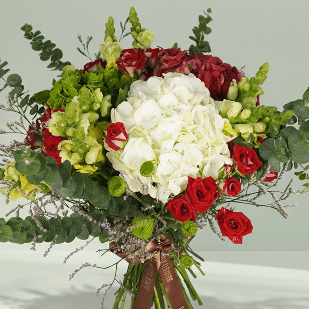 Mixed bouquet with white Hydrangeas, red Spray Roses, green Snapdragons, Limonium, Button Chrysanthemums and greenery.