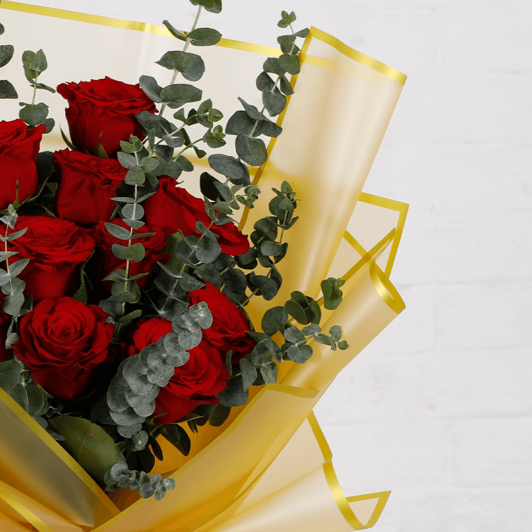 Bouquet of 10 fresh red roses with eucalyptus in a golden wrap.