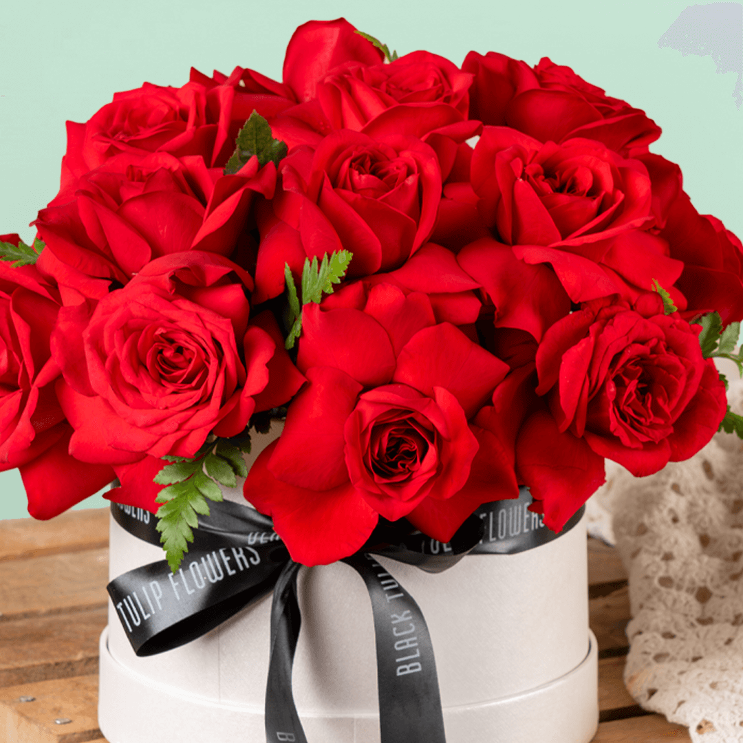 Fresh red roses arranged in a white round flower box with black ribbon