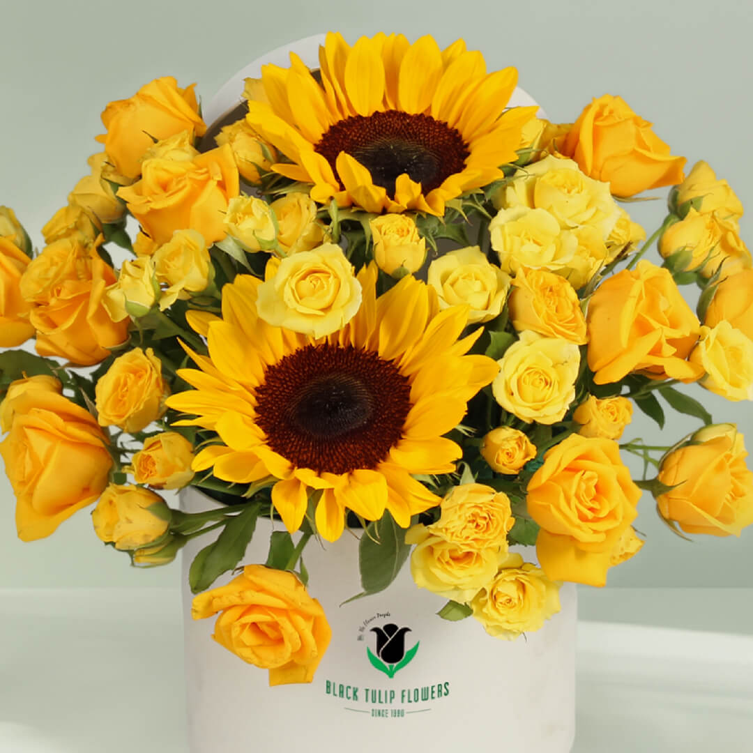 Yellow Sunflowers and Roses arranged with greenery in a white round flower box.