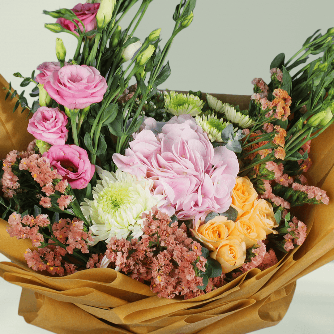 Pastel hydrangea, Eustoma, statice and chrysanthemums with greenery wrapped in rustic brown flower paper
