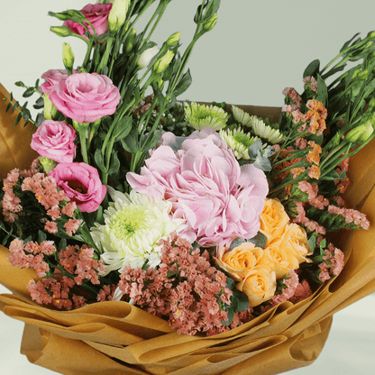 Pastel hydrangea, Eustoma, statice and chrysanthemums with greenery wrapped in rustic brown flower paper
