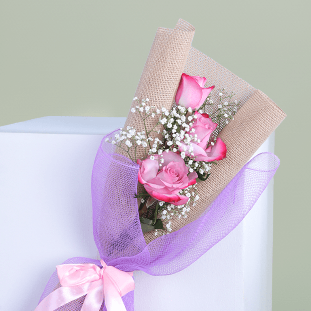Small bouquet of three premium pink roses with baby's breath in a elegant wrap.