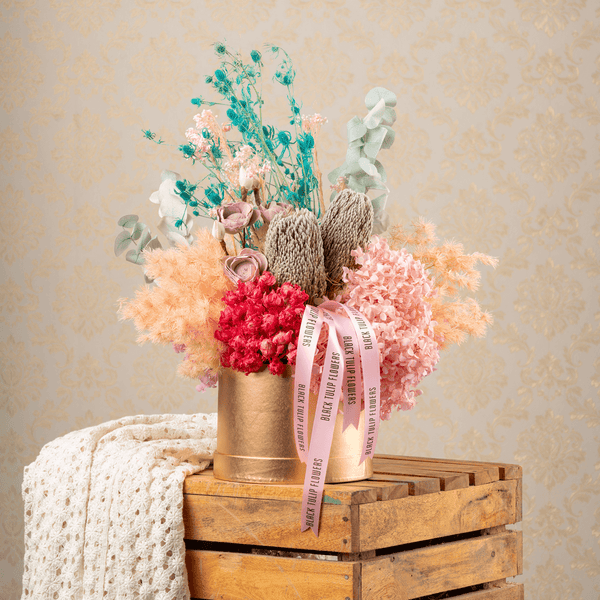 Assorted dried and preserved flowers arranged in a premium round gold box