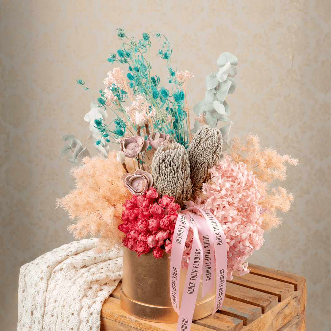 Assorted dried and preserved flowers arranged in a premium round gold box