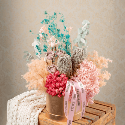 Assorted dried and preserved flowers arranged in a premium round gold box