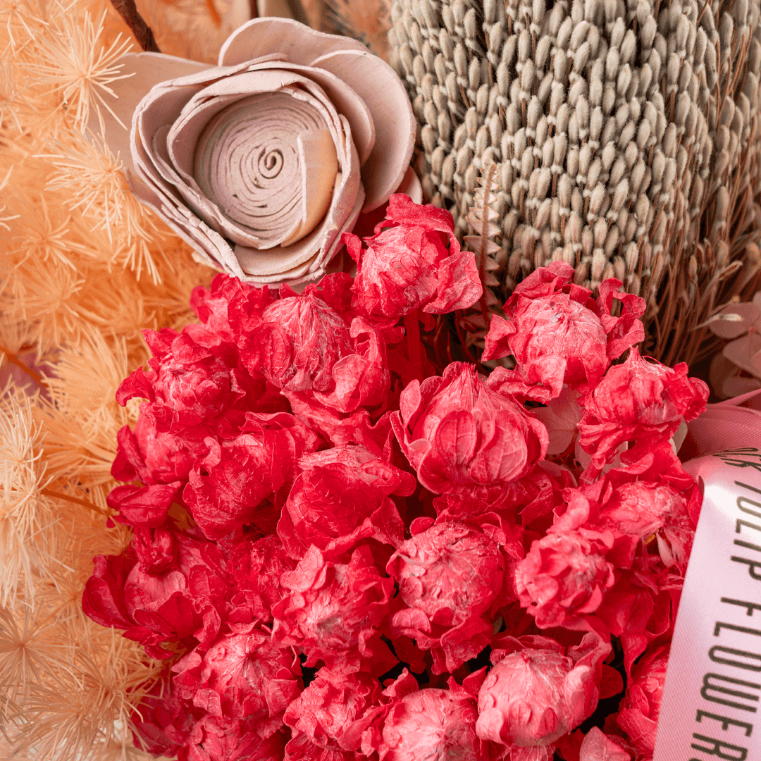 Assorted dried and preserved flowers arranged in a premium round gold box