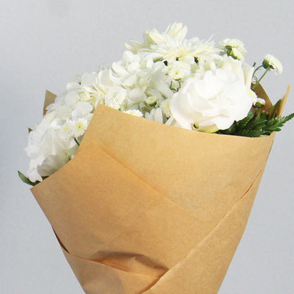 White Hydrangeas, Gerberas, Carnations and Chrysanthemums wrapped in natural-toned non-woven paper.