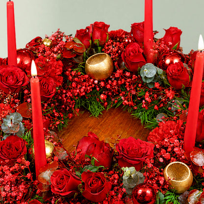 A fresh festive flower wreath with roses, carnations, eucalyptus, gypsophila, fresh greenery, and an LED taper candle.
