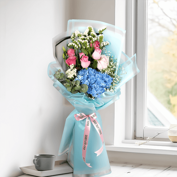 Pastel blue Hydrangea bouquet with pink Roses, Eustoma, Statice and white Gypsophila in Korean-style blue wrapping.