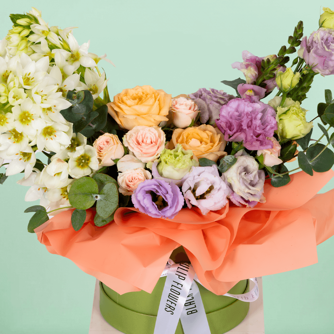Small round flower box arranged with assorted Roses, Eustoma, Ornithogalum and Eucalyptus.