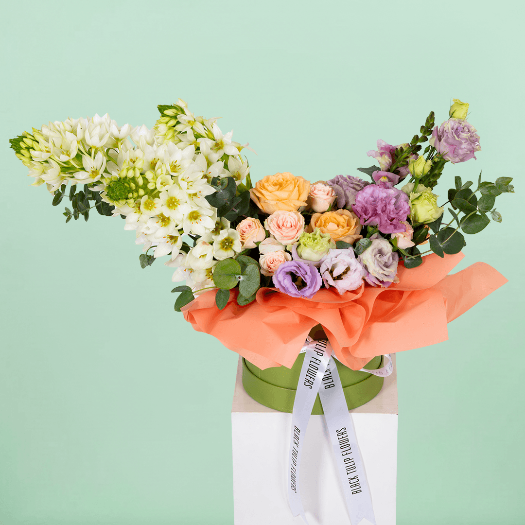Small round flower box arranged with assorted Roses, Eustoma, Ornithogalum and Eucalyptus.
