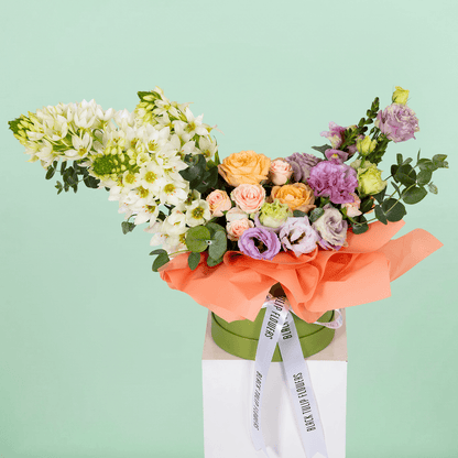 Small round flower box arranged with assorted Roses, Eustoma, Ornithogalum and Eucalyptus.