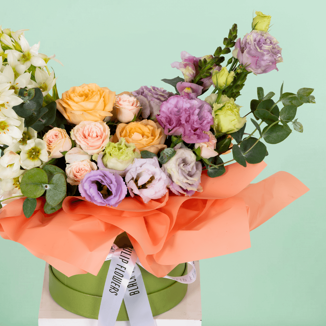 Small round flower box arranged with assorted Roses, Eustoma, Ornithogalum and Eucalyptus.