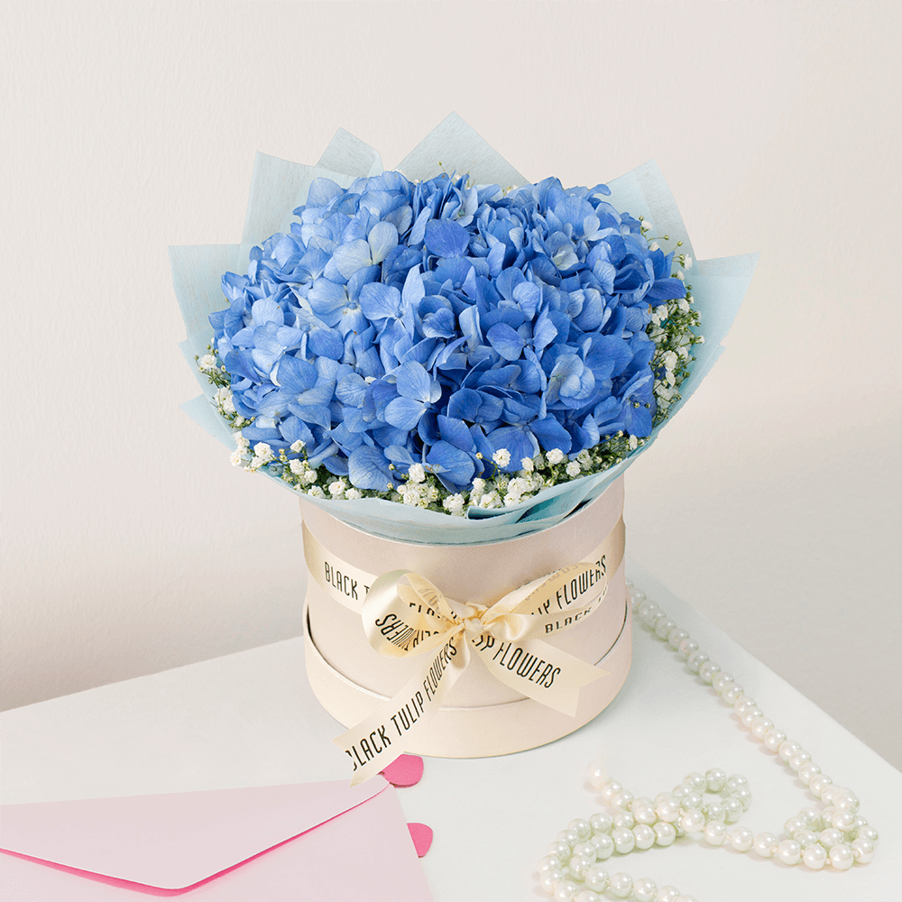 Blue Hydrangea and white Gypsophila arranged in an elegant flower box.
