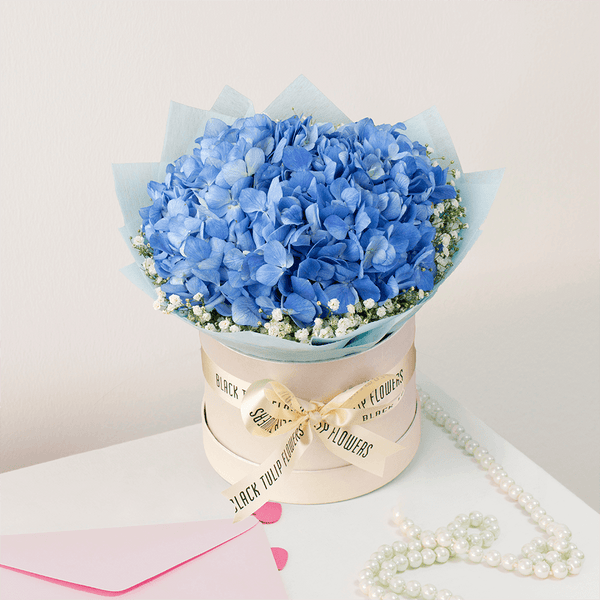 Blue Hydrangea and white Gypsophila arranged in an elegant flower box.