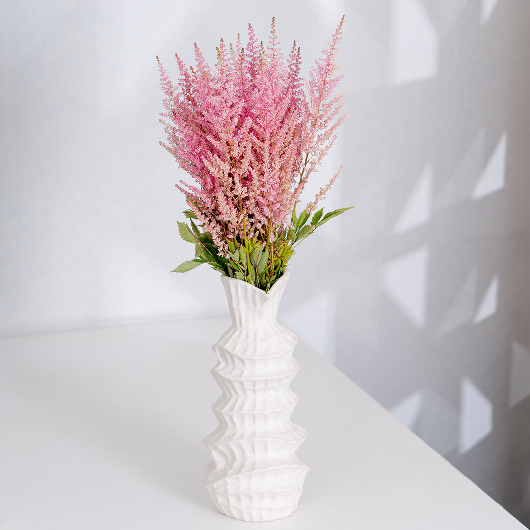 Fresh Astilbe cut flowers neatly arranged in brown paper wrapping