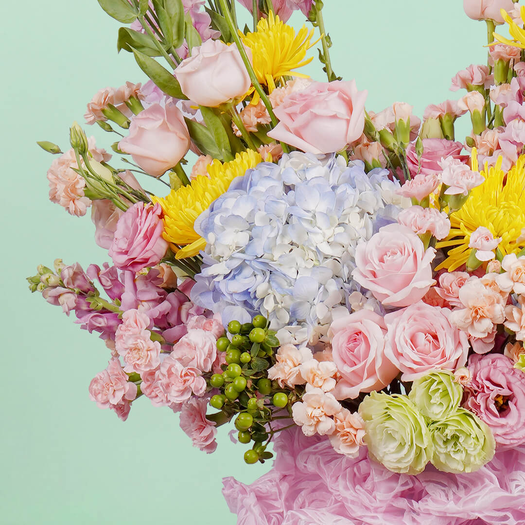 A white round box featuring 30 stems of hydrangeas, delphiniums, disbuds, roses, eustoma, spray carnations, and hypericum artistically arranged.