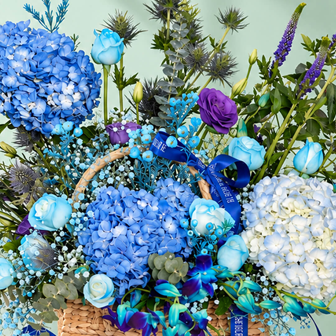 Rectangle basket filled with blue hydrangea, roses, orchid, veronica, and eustoma.