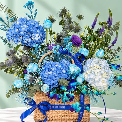 Rectangle basket filled with blue hydrangea, roses, orchid, veronica, and eustoma.
