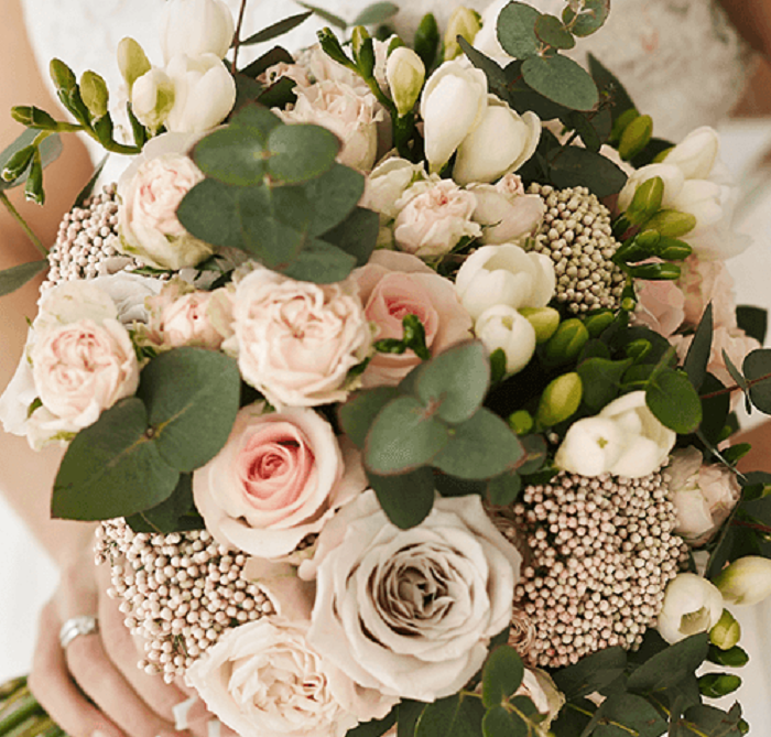 A hand-tied bouquet featuring blush pink roses, seasonal flowers and eucalyptus greenery.