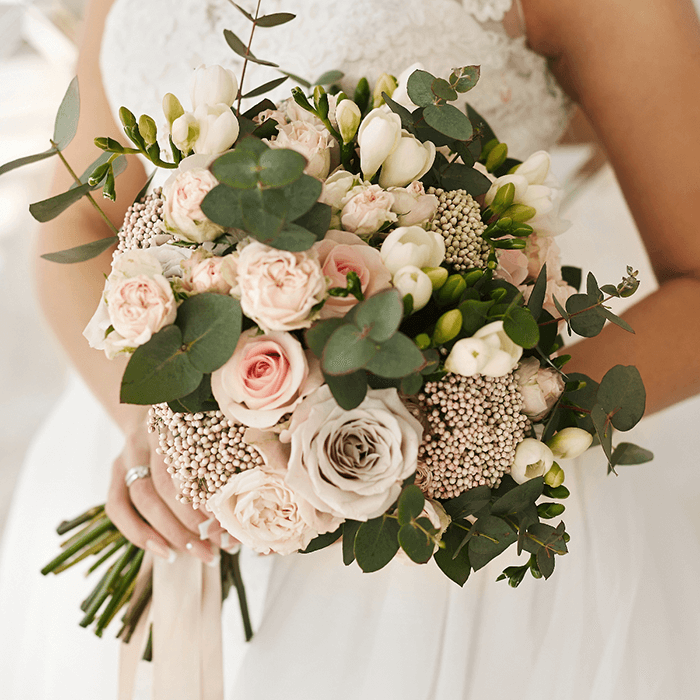 A hand-tied bouquet featuring blush pink roses, seasonal flowers and eucalyptus greenery.