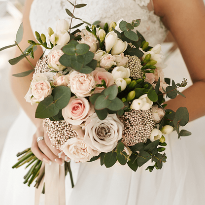 A hand-tied bouquet featuring blush pink roses, seasonal flowers and eucalyptus greenery.