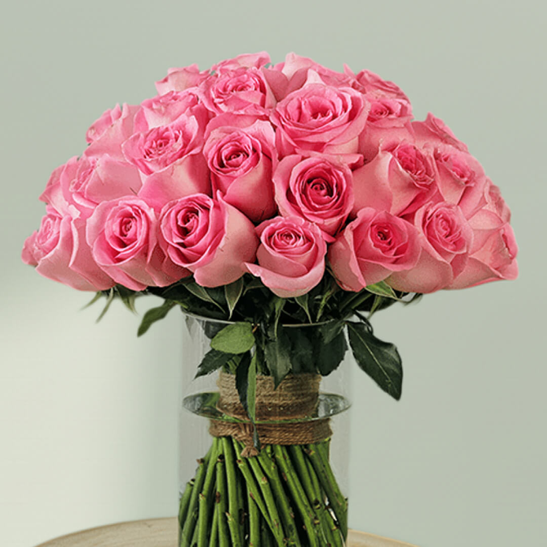 A vase arrangement showcasing 30 pink roses with lush green foliage.