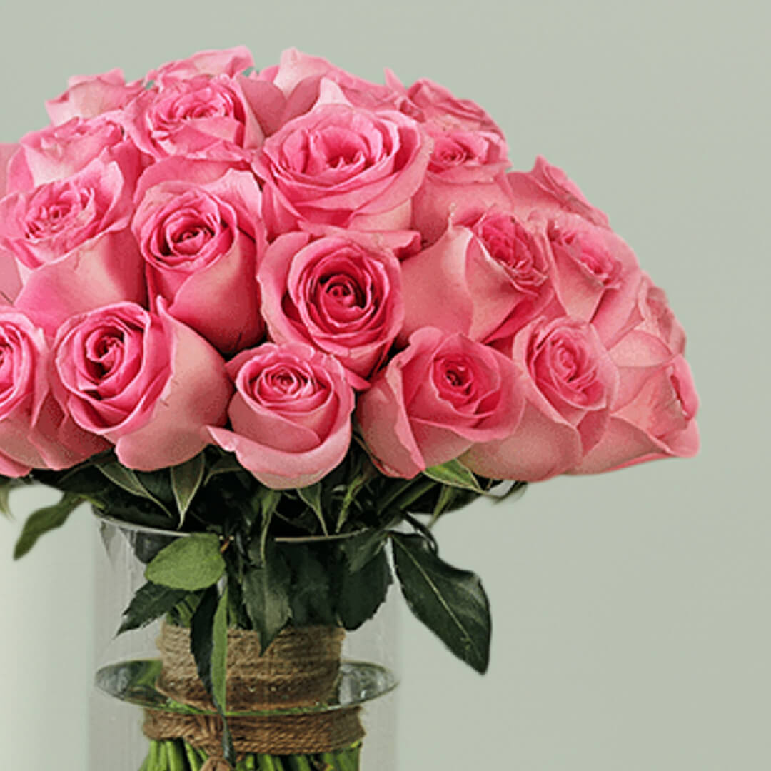 A vase arrangement showcasing 30 pink roses with lush green foliage.