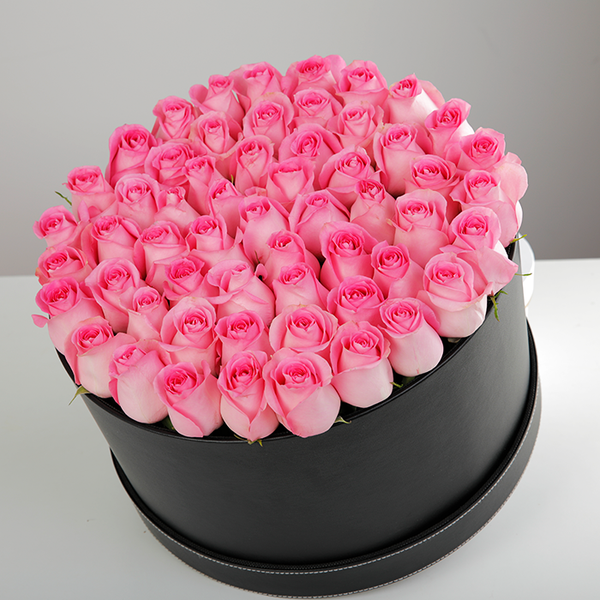 Round flower box featuring fresh pink roses in a sleek black base.