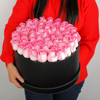 Round flower box featuring fresh pink roses in a sleek black base.