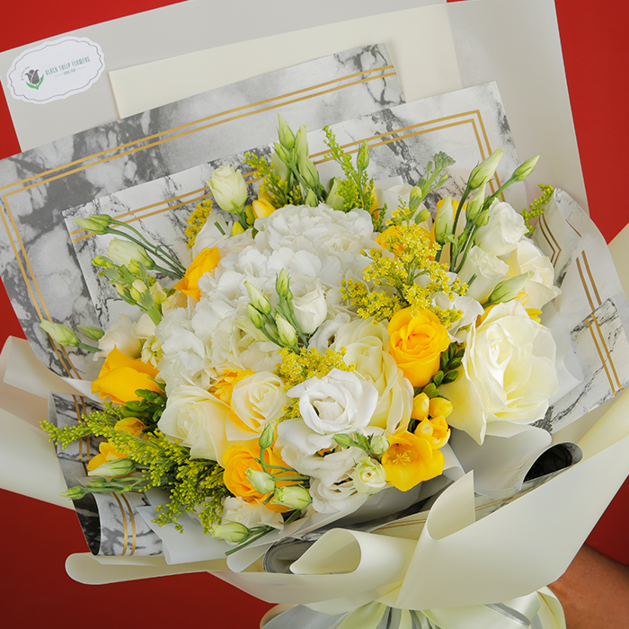 Bouquet featuring roses, Eustoma, golden rod and fillers in white non-woven wrapping, finished with elegant ribbons.