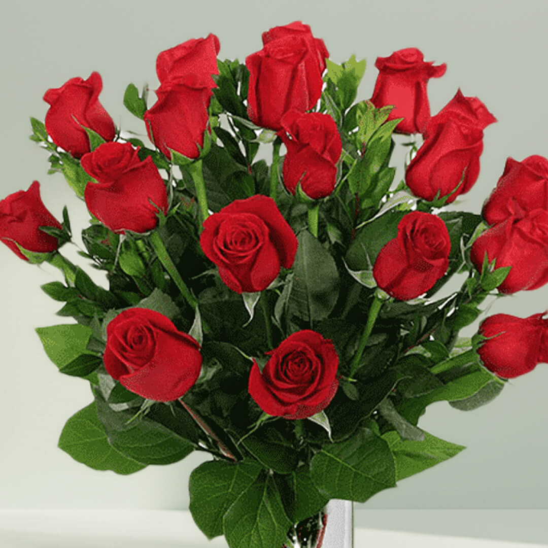 Vase arrangement featuring 20 red roses and lush greenery in a transparent glass cylinder vase.