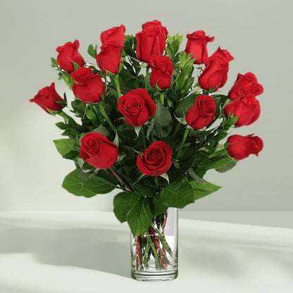 Vase arrangement featuring 20 red roses and lush greenery in a transparent glass cylinder vase.