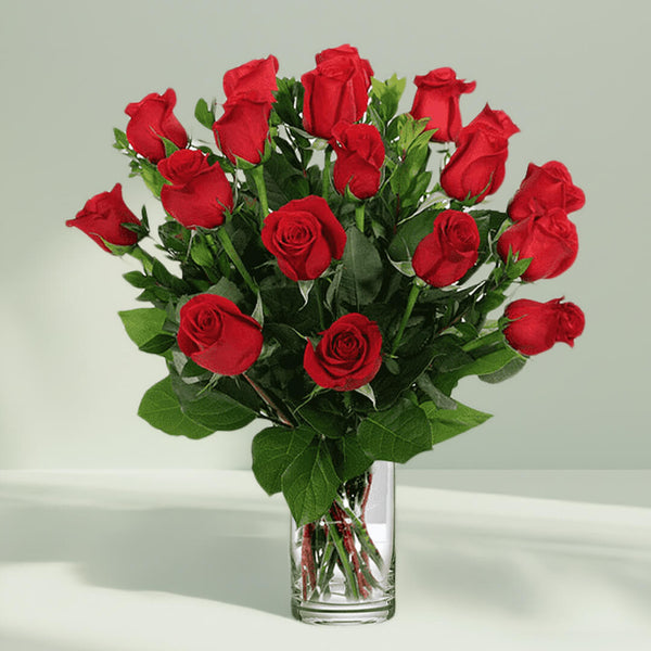 Vase arrangement featuring 20 red roses and lush greenery in a transparent glass cylinder vase.