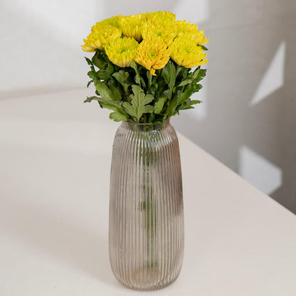 Fresh Disbud flowers neatly arranged in ribbed clear glass vase.