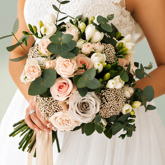 Exotic bridal bouquet with blush pink roses, seasonal flowers and fresh eucalyptus greenery for weddings