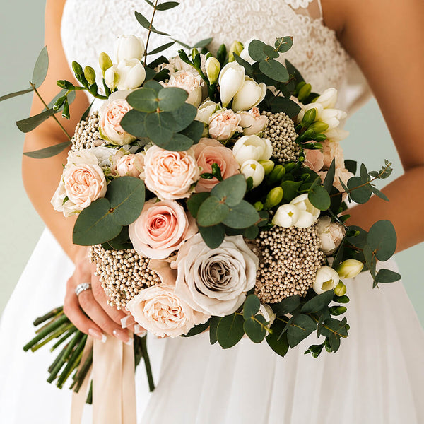 Exotic bridal bouquet with blush pink roses, seasonal flowers and fresh eucalyptus greenery for weddings
